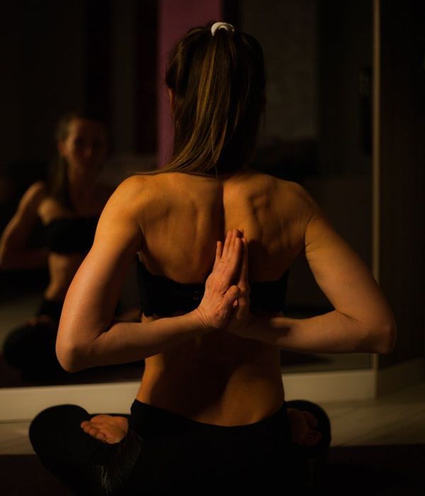 A calm person in a meditative yoga pose in a dark room.
